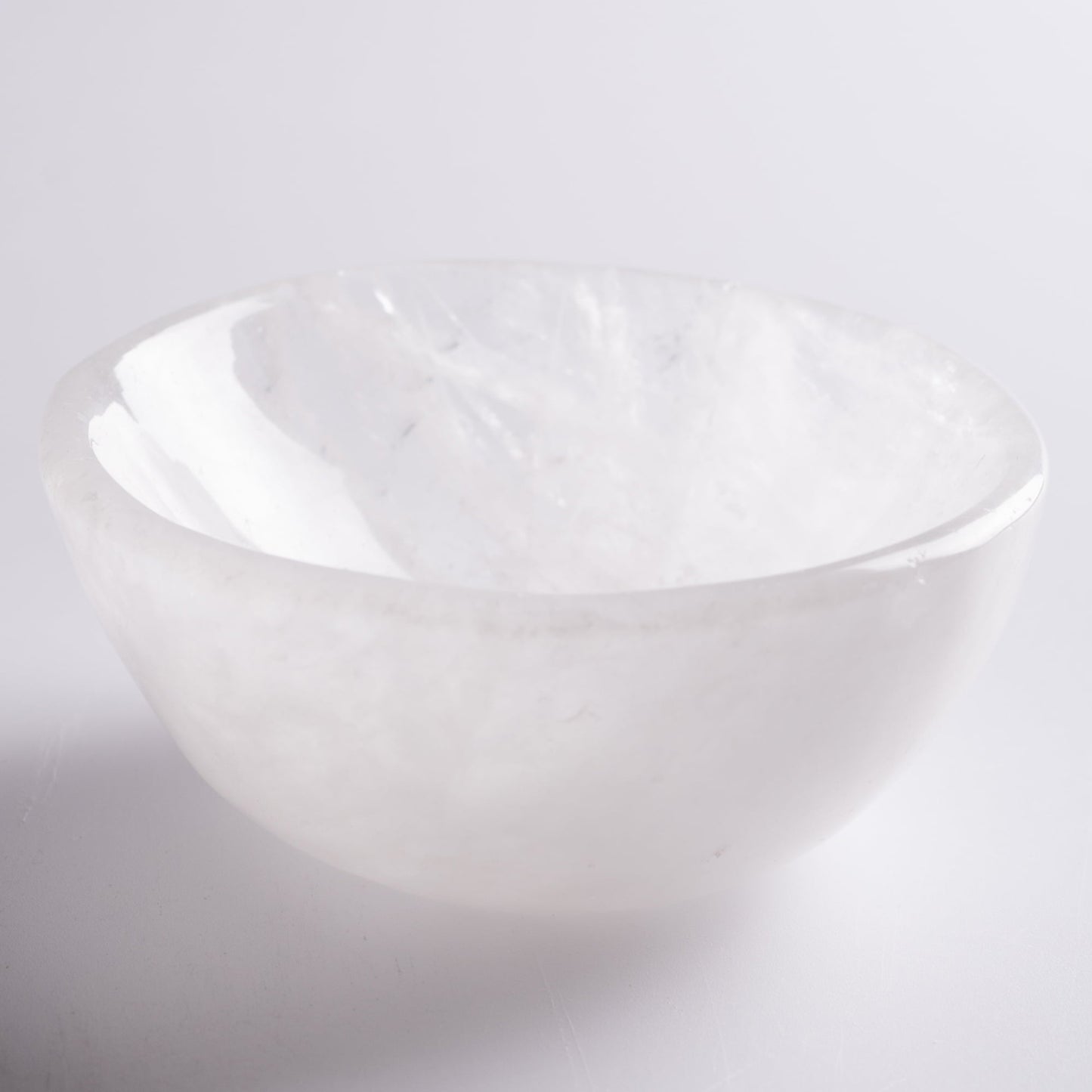 Selenite cleansing bowl holding crystals on altar, radiating light.