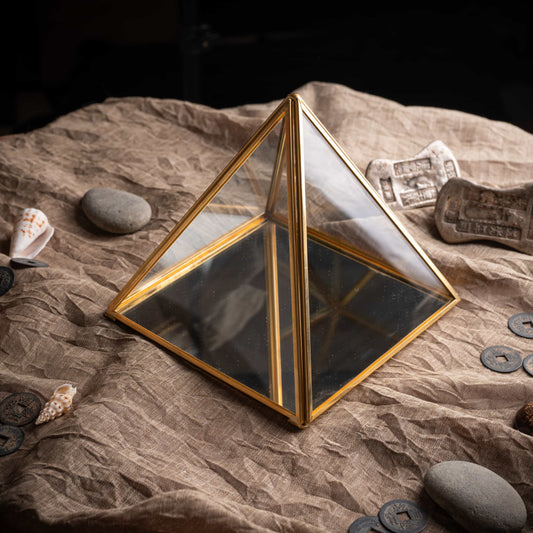Close-up of glass pyramid charging box, brass edges and mirrored surface.
