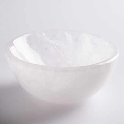 Selenite cleansing bowl holding crystals on altar, radiating light.